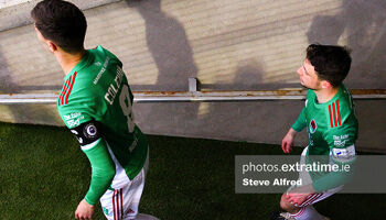 Cian Coleman, wearing the Head in the Game armband for Mental Health Awareness Month, and Jack Baxter of Cork City, enter the pitch before the game.