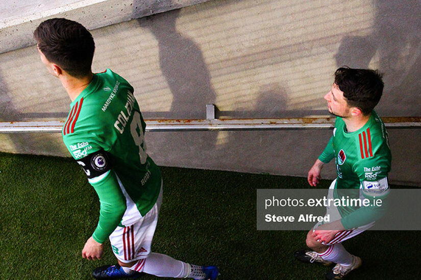 Cian Coleman, wearing the Head in the Game armband for Mental Health Awareness Month, and Jack Baxter of Cork City, enter the pitch before the game.