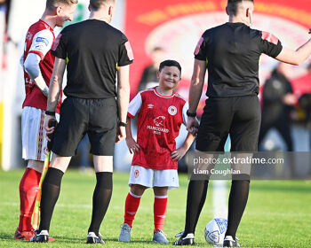 A smiling Saints mascot standing between skipper Ian Bermingham and referee Rob Hennessy ahead of the Athletic's 4-0 win over City last April